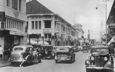 an old black and white photo of cars driving down the street