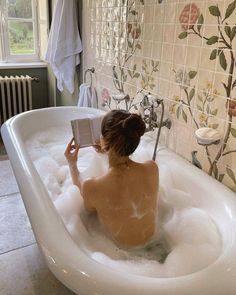 a woman sitting in a bathtub reading a book