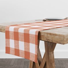 an orange and white checkered table cloth on a wooden dining table with two plates