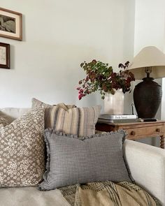 a living room with couches and pillows on the floor next to a vase filled with flowers