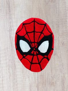 a close up of a spiderman face on a wooden surface