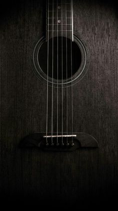 an acoustic guitar in the dark with its fret and strings still attached to it