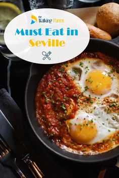 two fried eggs are in a skillet with sauce and parsley on the side