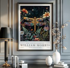 a framed art print of a dragonfly on a wall above a table with flowers and books