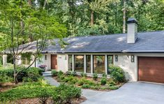 a house in the woods with lots of trees and bushes on either side of it