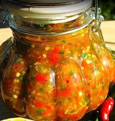 a glass jar filled with soup sitting on top of a table next to a slice of lemon