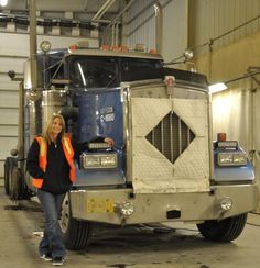 a woman standing in front of a semi truck