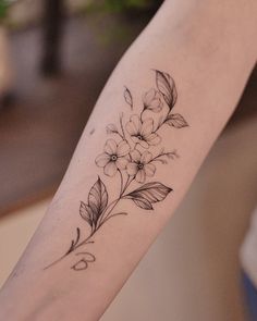 a woman's arm with flowers and leaves on the left side of her arm