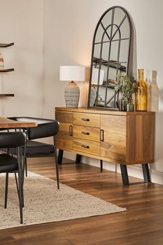 a dining room table and chairs with a mirror on the wall above it, in front of a wooden dresser