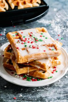 a stack of waffles with white icing and sprinkles on a plate