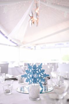 a snowflake centerpiece sits on top of a table set with glasses and silverware