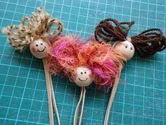 three hair pins with faces on them sitting next to each other in the shape of sheeps