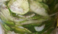 a jar filled with sliced cucumbers and seasoning on top of a table