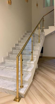 a white marble staircase with gold handrails