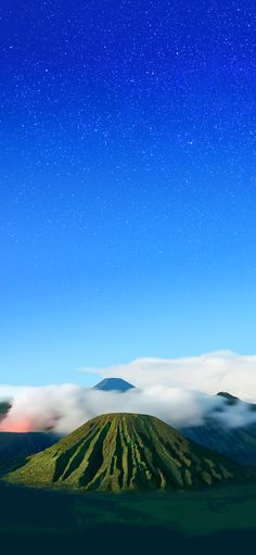 the night sky is filled with stars and clouds over a mountain range in the distance