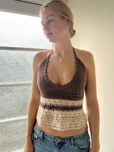 a woman standing in front of a window wearing a crocheted halter top