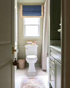 a white toilet sitting next to a window in a bathroom under a blue blinder