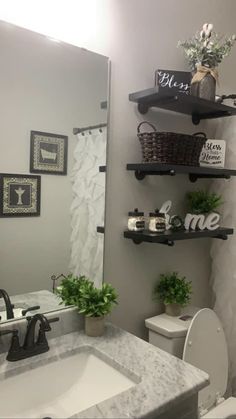 a white toilet sitting next to a bathroom sink under a mirror with shelves above it