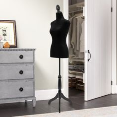 a mannequin on a stand in front of a dresser and closet with clothes