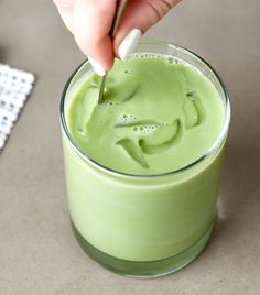 a person is dipping something into a green drink