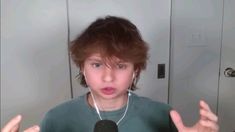 a young boy with headphones on is making a face and holding his hands out