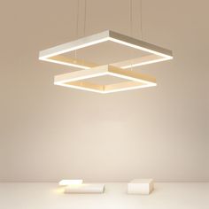 three square lights suspended from the ceiling in an empty room with white walls and flooring