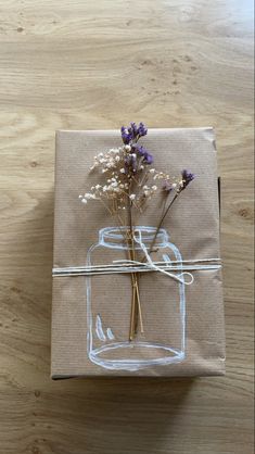 a gift wrapped in brown paper and tied to a string with dried flowers on it