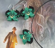 some green and black earrings with an image of a man in a hat on them