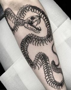 a man's arm with a black and white tattoo design on the left forearm