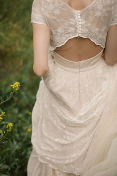 the back of a woman's dress with flowers in the foreground and grass in the background