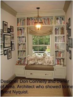 a window seat in front of a bookshelf filled with lots of books and pictures