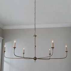 a chandelier hanging from the ceiling in a room with white walls and windows