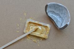 a broken spoon sitting on top of a table next to an empty container with something in it