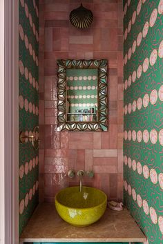 a bathroom with a green sink and pink wallpaper on the walls, along with a mirror above it