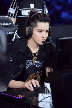 a young man wearing headphones sitting in front of a computer