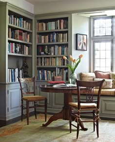 a room with a table, chairs and bookshelves