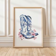 a blue and white boot with pink flowers on it is framed in a wooden frame