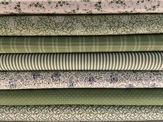 a stack of green and white fabrics with flowers on them, all in different colors