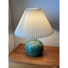 a green lamp sitting on top of a wooden table