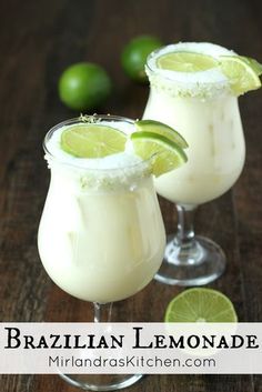 two glasses filled with white liquid and limes