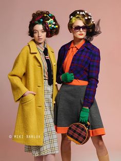 two women standing next to each other in front of a pink background wearing colorful clothing