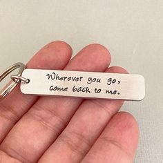 a hand holding a keychain that says wherever you go comes back to me