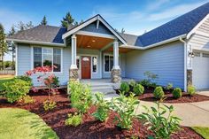 a house with landscaping in front of it and blue siding on the side of the house