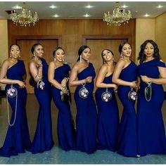 a group of women standing next to each other wearing blue dresses and holding purses