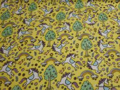 a yellow fabric with unicorns and trees on it