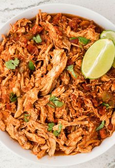 a white bowl filled with shredded chicken and garnished with cilantro