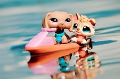 two little toys are sitting in the water next to each other on a toy boat