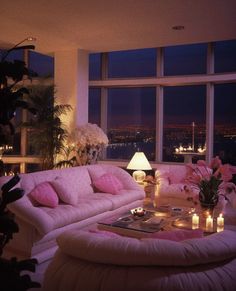 a living room filled with lots of furniture next to a window covered in pink pillows