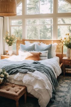 a bed with white and blue comforters in a bedroom next to a large window