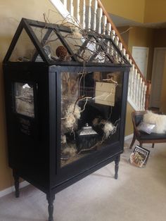 a house made out of an old cabinet with some stuff in it and decorations on top